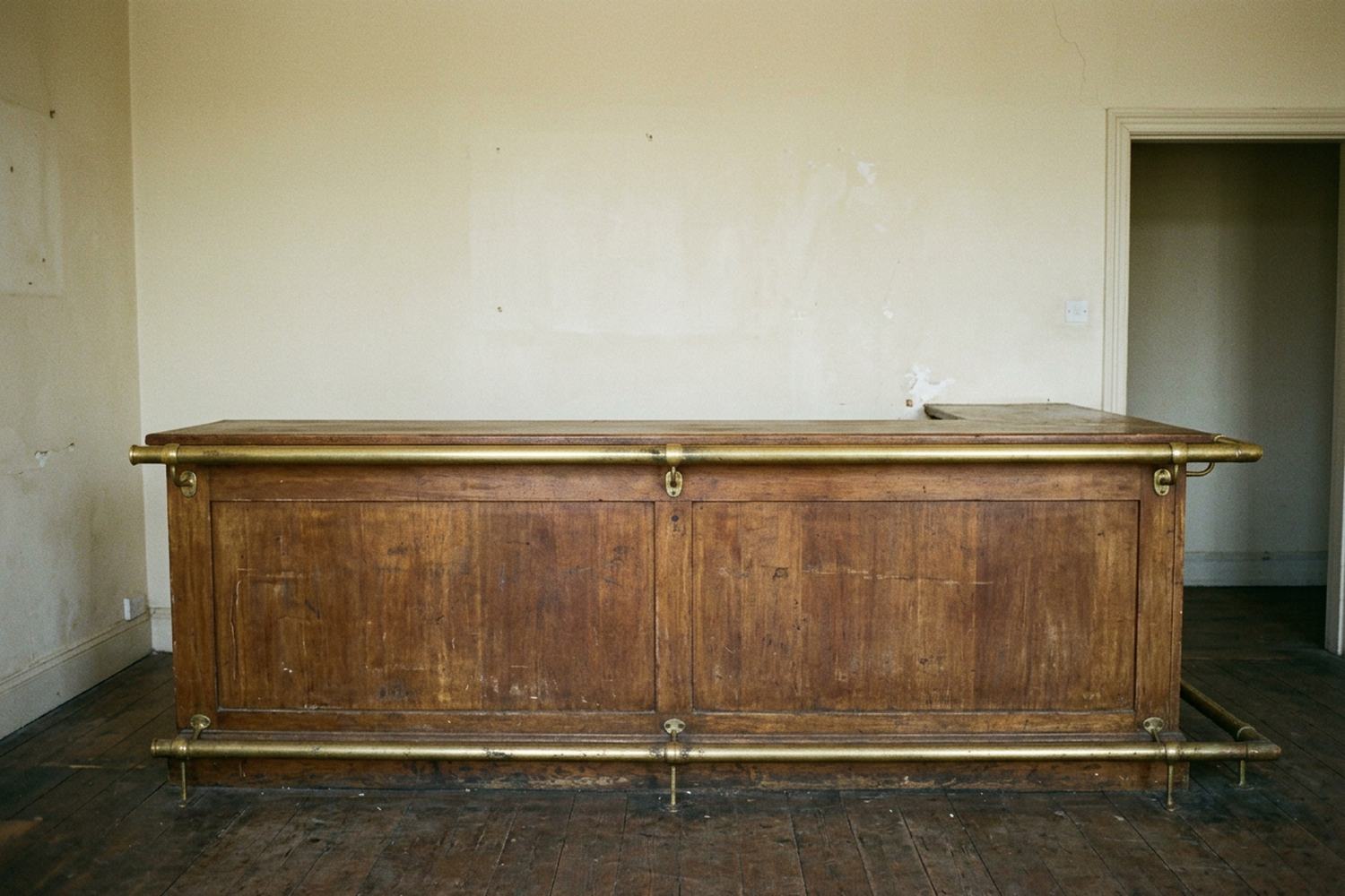 A worn wooden counter with a brass rail along its front edge.