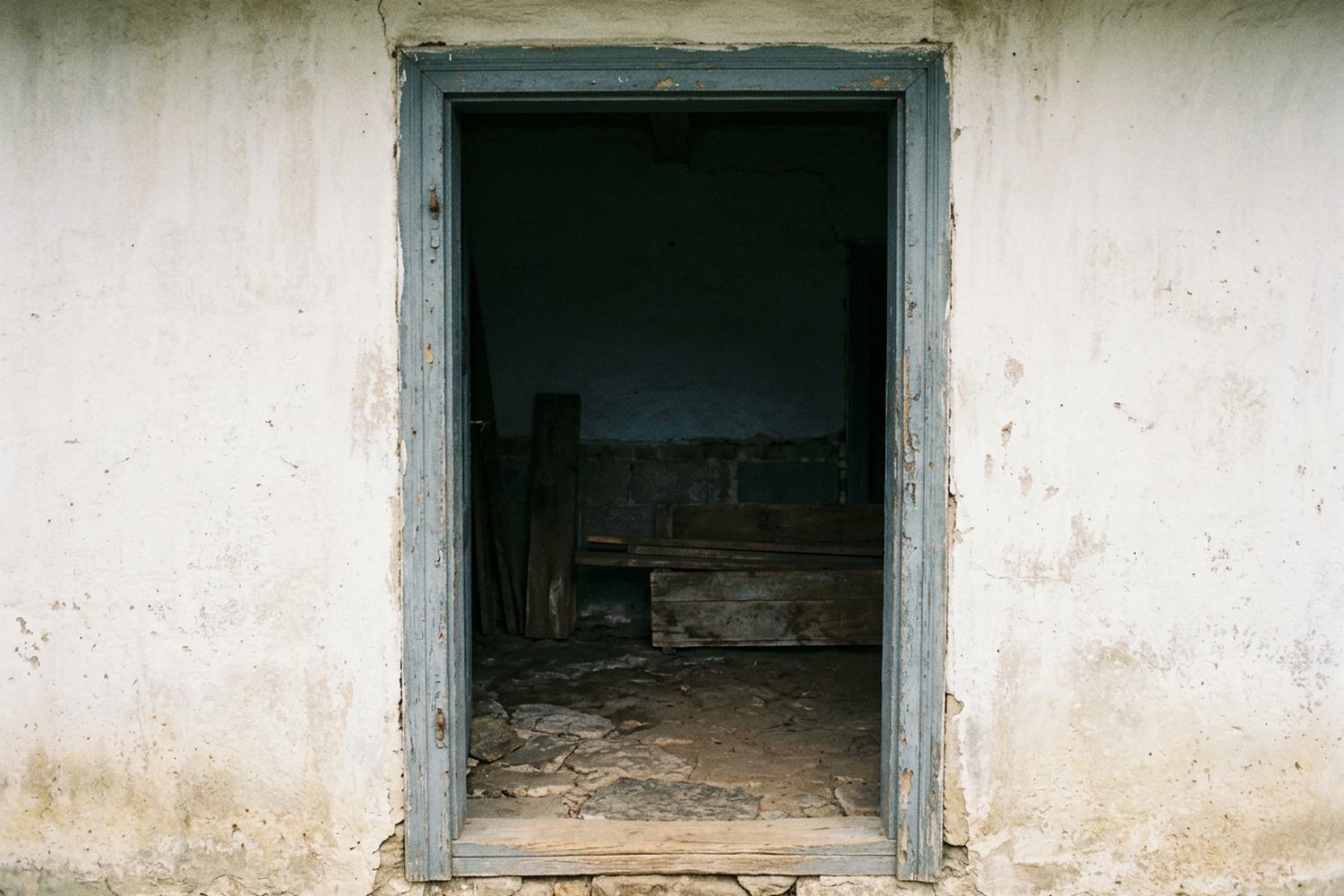 A painted doorframe with the door removed, opening on shade.